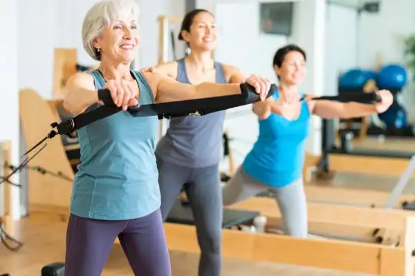Toning Arms After 60: Empowering Womens Fitness Through Effective Weight Training 2 older woman doing weight training Leicester and resistance in the gym to tone upper arms
